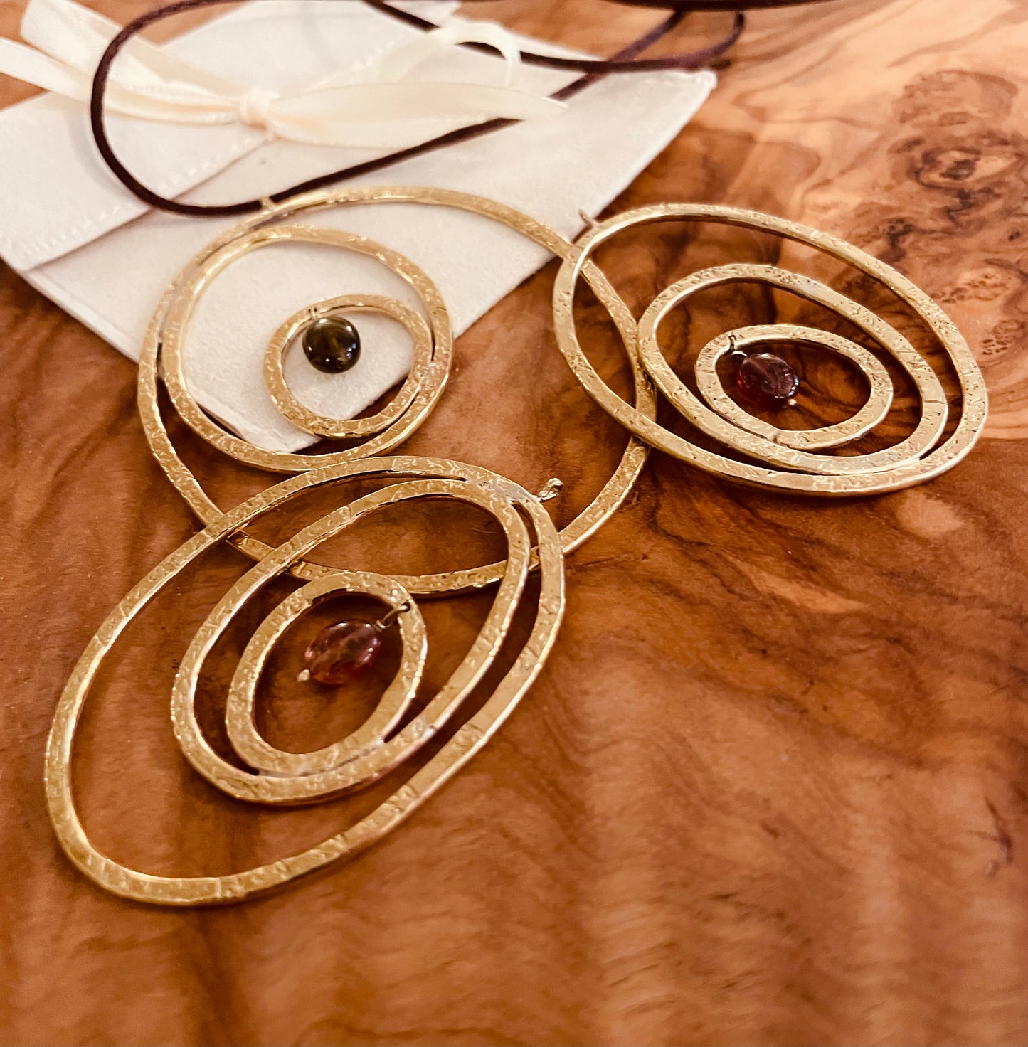 "Silenzi in orbita... Nelle orbite vuote, stelle di silenzio, tracce di un passato che sfugge e ritorna." - Linea 'Orbite': ciondolo, orecchini e anello in ottone martellato con tormalina.