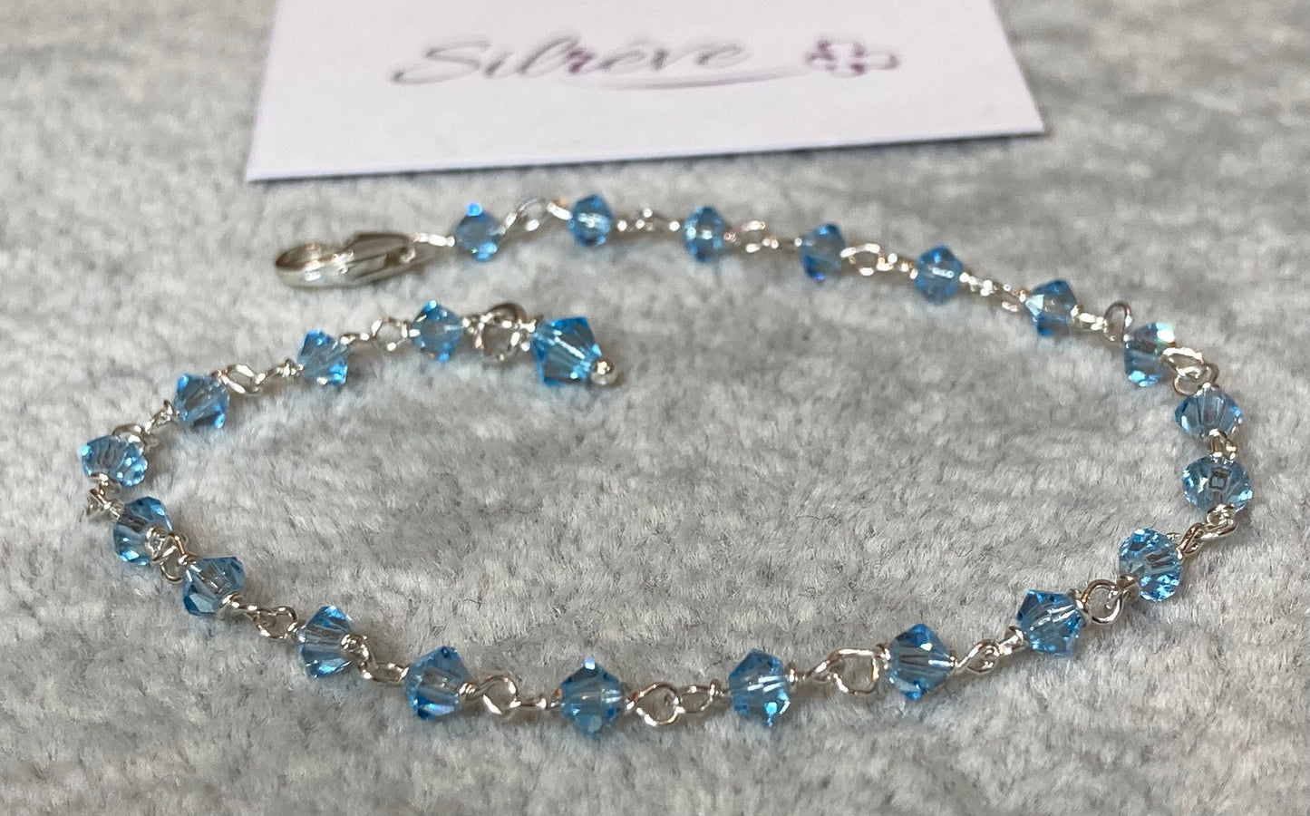 Braccialetto nodo orefice in Ag. 925, impreziosito con piccoli cristalli colorati.